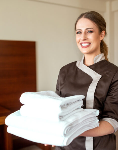 Hotel maid carrying fresh clean towels to accommodate her guests