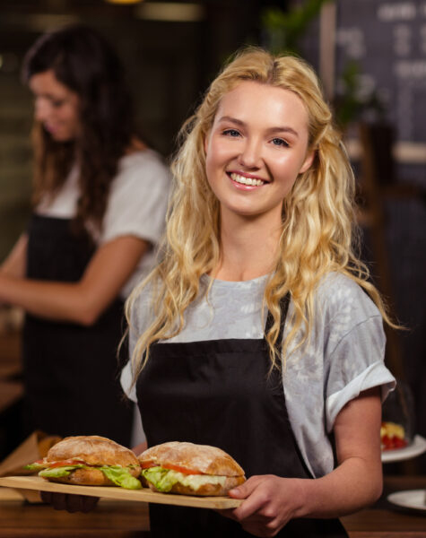 Pretty waitress holding a tray with sandwiches at the coffee shop